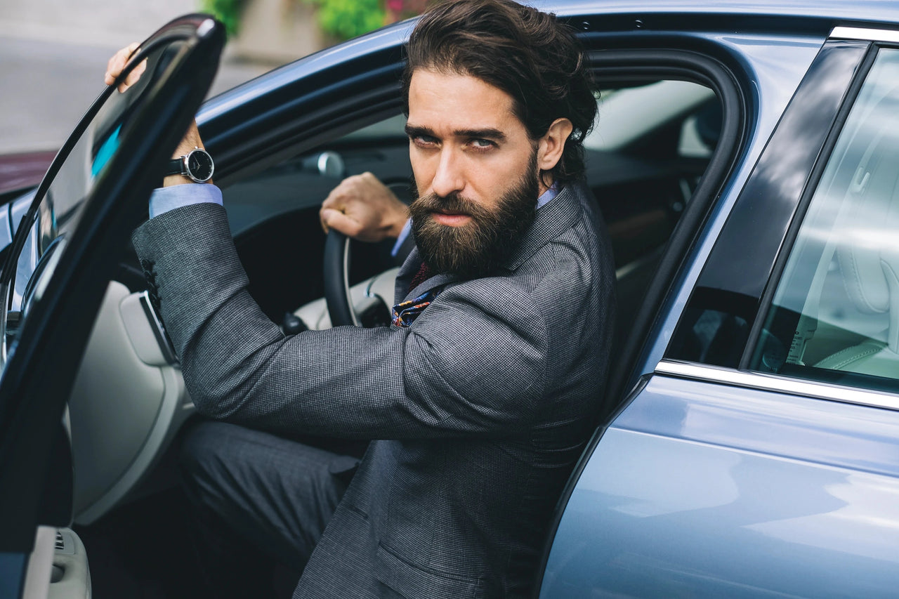 Man wearing a blazer while stepping out of a car